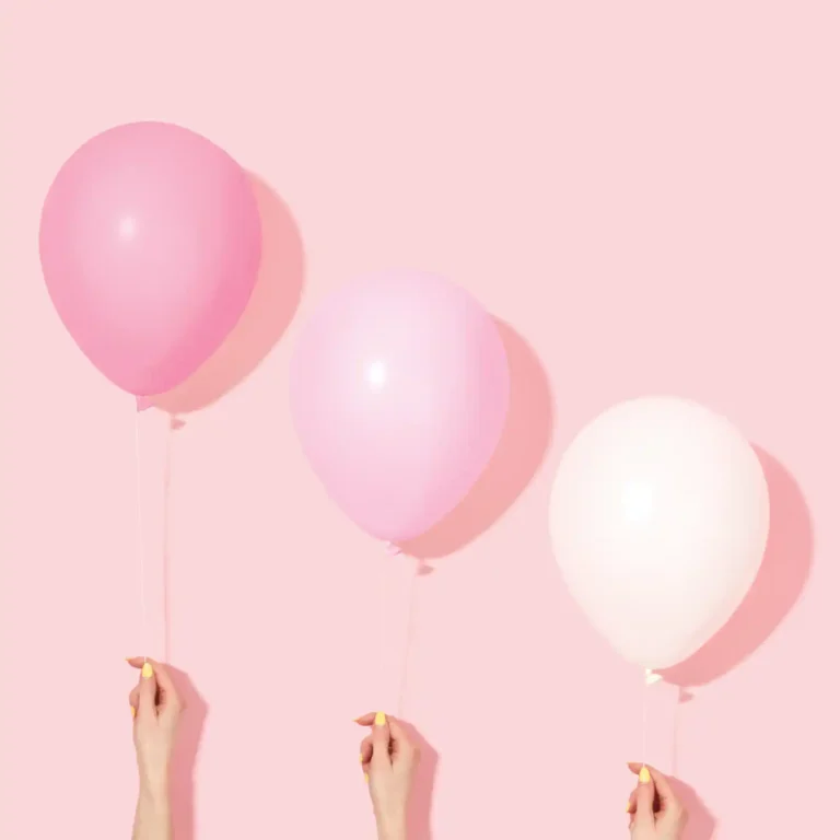 Des ballons roses et blancs sur un fond rose